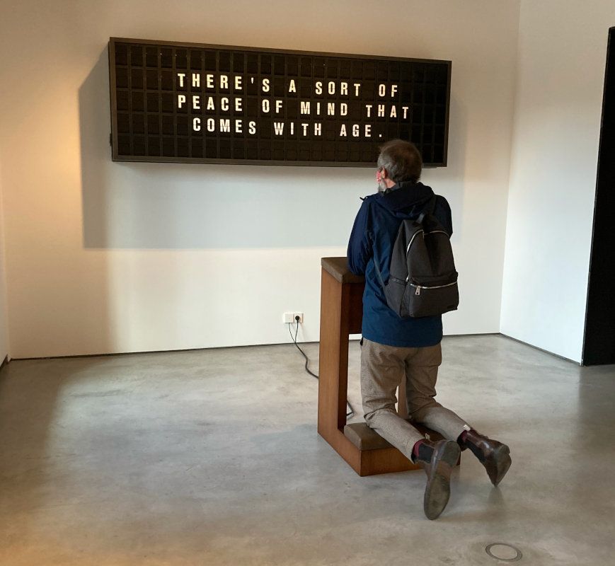 man kneeling in an art installation in front a mechanical display